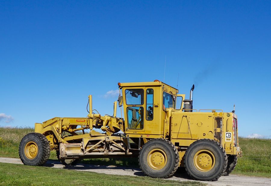 Motor grader shaping the surface of a gravel lane
